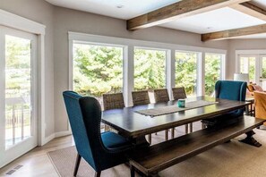 A dining area with a large table, chairs, and a view of greenery outside. - Dog-friendly house with private heated outdoor pool, hot tub & Ping-Pong (Grand Beach)