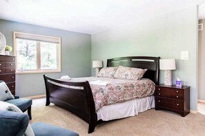 A bedroom with a bed, two bedside tables, a chair, a window, and a dresser. - Dog-friendly house with private heated outdoor pool, hot tub & Ping-Pong (Grand Beach)