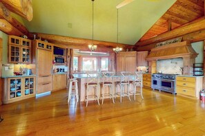 A spacious kitchen with wooden cabinets, a central island with bar stools, a large stove, and a microwave. - Grand cabin with lake view, pond, wood fireplace & AC, & fast WiFi (Coloma Charter Township)