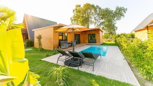 A modern house with a swimming pool, patio furniture, and a covered outdoor seating area.
