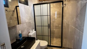 A bathroom with a shower, toilet, sink, and mirror.