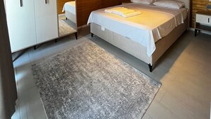 A bedroom with a bed, a wardrobe, a mirror, a ceiling fan, and an air conditioning unit.