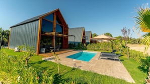 Ett modernt hus med pool, utomhusmöbler och en trädgård.