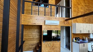 En interiör i loftstil med en entresol, ett öppet vardagsrum och ett kök.