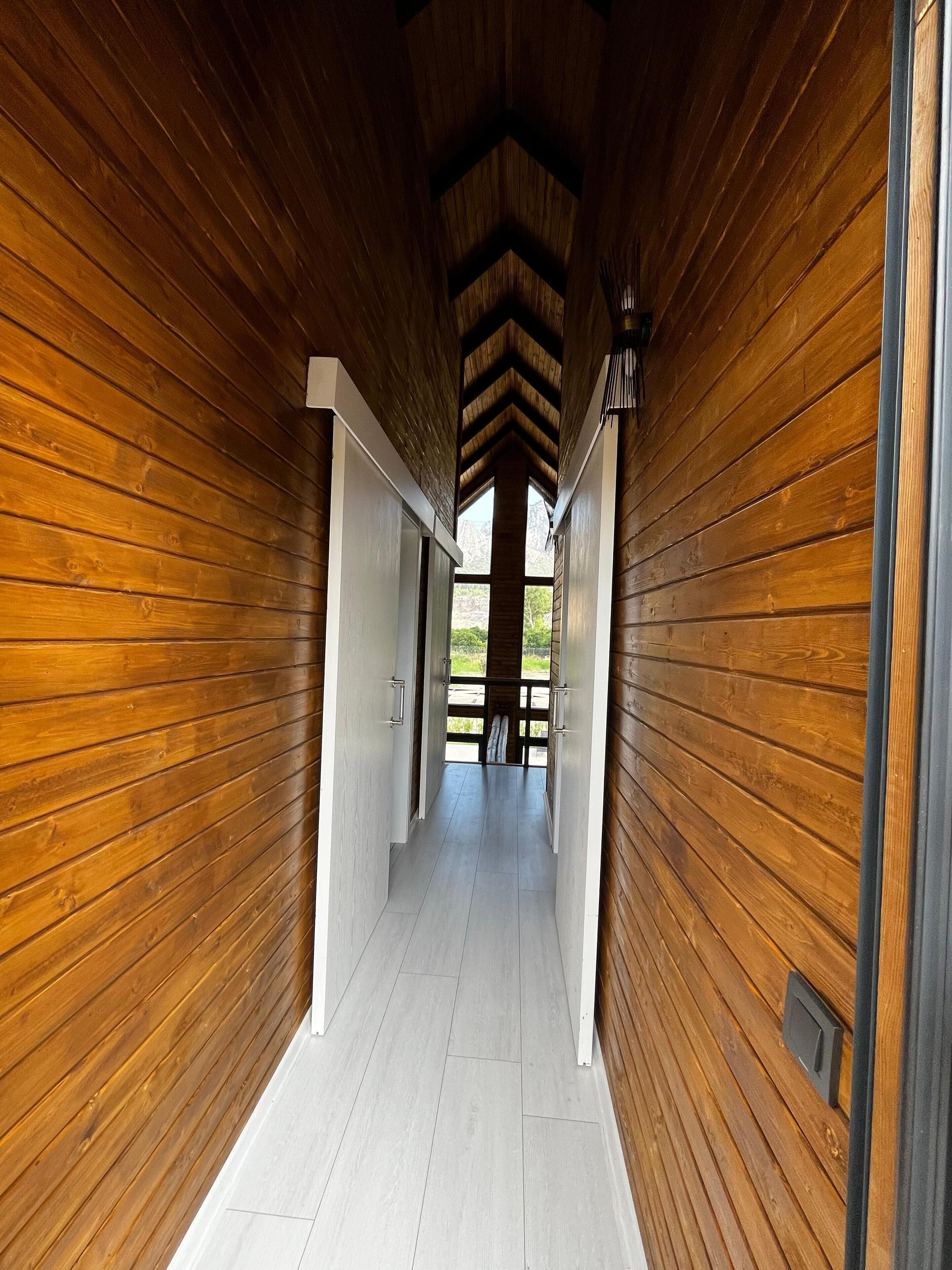 A wooden hallway with a high ceiling and a view of the outdoors.