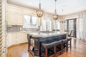 A spacious kitchen with a large island, bar stools, and pendant lighting. - Classic home w/ private hot tub, sauna, & outdoor fireplace - 350 feet to beach (New Buffalo)