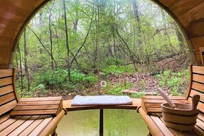 Une structure circulaire en bois, comprenant deux bancs en bois et une table sur laquelle se trouvent une serviette et un bol en bois.
