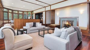 Ein modernes Wohnzimmer mit Kamin, Holzwänden und großen Fenstern.