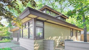 Ein zweistöckiges Haus mit einer Veranda, großen Fenstern und einem geneigten Dach.