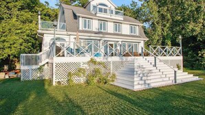 A two-story house with a covered porch and a staircase leading to the entrance. - Upper-level Duplex on Lake Michigan w/ patio, gas grill & WIFI (Coloma)