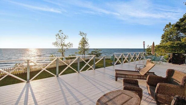 A wooden deck with outdoor furniture, a railing, and a view of the sea. - Upper-level Duplex on Lake Michigan w/ patio, gas grill & WIFI (Coloma)