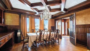 A dining room with a wooden table and chairs, a chandelier, and large windows. - Upper-level Duplex on Lake Michigan w/ patio, gas grill & WIFI (Coloma)