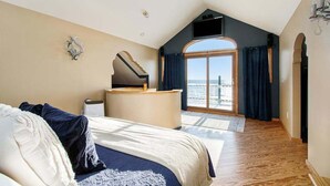 A bedroom with a bed, a desk, a TV, and a view of the sea. - Upper-level Duplex on Lake Michigan w/ patio, gas grill & WIFI (Coloma)