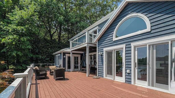 A two-story house with a deck, large windows, and a covered outdoor area.