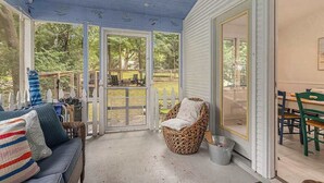 En overdækket veranda med sofa, fletstol og spisebord.