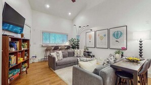 Una sala de estar con sofá, mesa de comedor y televisor.