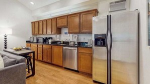 Una cocina moderna con armarios de madera, electrodomésticos de acero inoxidable y un sofá gris.