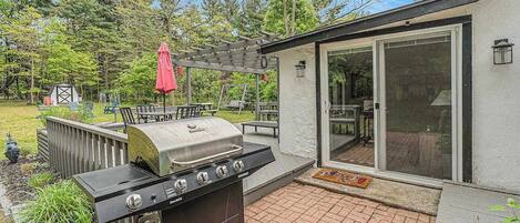 A backyard with a grill, patio furniture, and a covered seating area.