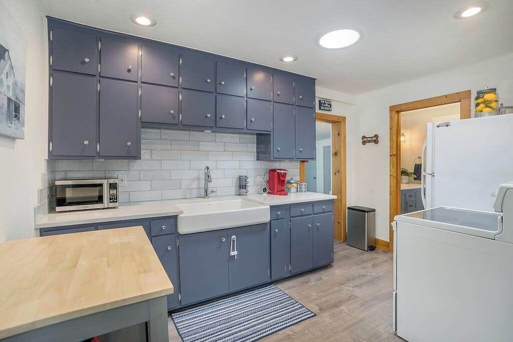 A modern kitchen with grey cabinets, a white countertop, a microwave, a coffee maker, and a refrigerator.