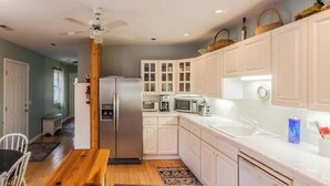 Cucina con mobili bianchi, frigorifero, microonde e zona pranzo con tavolo e sedie.