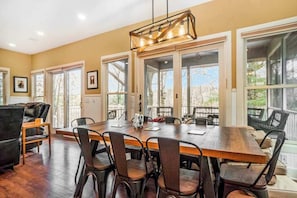 A dining area with a wooden table, chairs, and a pendant light. - Dreamy retreat near the lake with spacious deck, foosball, Ping-Pong & kayaks (Saugatuck)