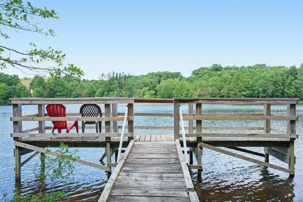 A wooden pier extending into a lake with a view of a forested area. - Dreamy retreat near the lake with spacious deck, foosball, Ping-Pong & kayaks (Saugatuck)