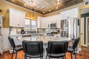 A kitchen with white cabinets, a central island, black chairs, a stainless steel refrigerator, and a microwave. - Dreamy retreat near the lake with spacious deck, foosball, Ping-Pong & kayaks (Saugatuck)