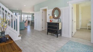 A spacious living area with a staircase, a wooden coffee table, a mirror, and a door leading to another room. - Gorgeous home w/ furnished patio, decks, & open living space - easy beach access (South Haven)