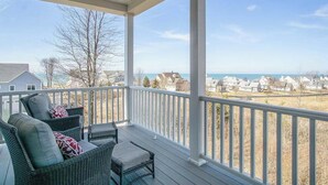 A covered porch with wicker furniture and a view of houses and water. - Gorgeous home w/ furnished patio, decks, & open living space - easy beach access (South Haven)