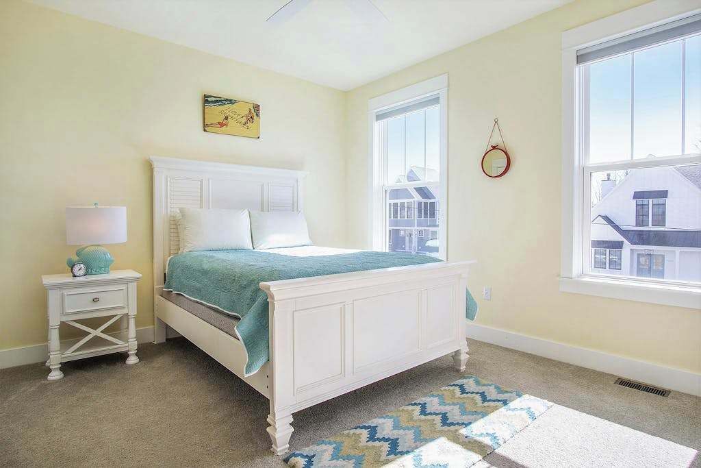 Une chambre à coucher avec un lit, une table de chevet, une lampe, une fenêtre et une vue sur les bâtiments.