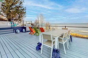 A deck with a table and chairs, gas cylinders, and a view of the water. - Lake Michigan Retreat w/ stunning views, hot tub, & large patio! (Michiana)