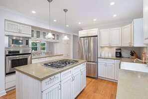 A modern kitchen with white cabinetry, stainless steel appliances, and a central island. - Stylish & Well-Equipped Home with Private Outdoor Pool, WiFi, Deck, Gas Grill (Lakeside)