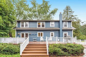 A two-story house with a porch, white railings, and a sign reading 'Beach House.' - Stylish & Well-Equipped Home with Private Outdoor Pool, WiFi, Deck, Gas Grill (Lakeside)