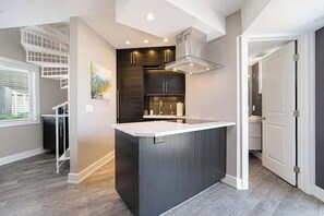 A modern kitchen with a central island, built-in appliances, and a staircase. - Updated condo with well-equipped kitchen, pool, firepits, grill, & gas fireplace (Douglas)