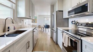 Una cocina moderna con electrodomésticos de acero inoxidable, armarios blancos y una isla central.