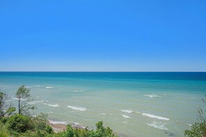 Blick auf die Küste mit blauem Himmel, sandigem Strand und grüner Vegetation.