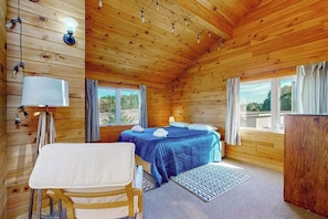 Una habitación de cabaña de madera con una cama, una mesa y un escritorio.