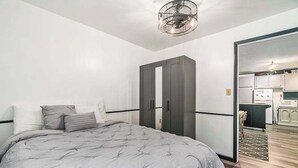 A bedroom with a bed, wardrobe, and a view into the kitchen. - Cardinal Cabin | House in Honor (Honor)