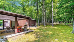 A wooden cabin with a covered patio, a barbecue grill, and a stone pathway leading to the entrance. - Cardinal Cabin | House in Honor (Honor)