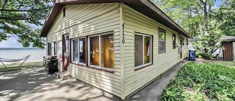 A small, single-story building with a number '4720' on the side, a front porch, and a view of a body of water.