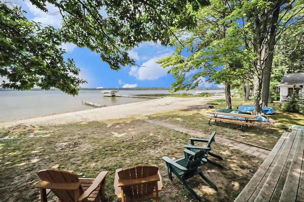 A lakeside deck with chairs, a table, and a covered area.