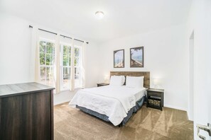 A bedroom with a bed, bedside tables, a nightstand, a dresser, and two framed pictures on the wall. - Secluded & contemporary cottage with a washer/dryer, central AC, & firepit (Honor)