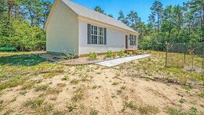A single-story house with a gabled roof, a front porch, and a paved driveway. - Secluded & contemporary cottage with a washer/dryer, central AC, & firepit (Honor)
