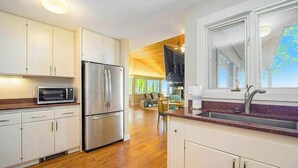 Una cocina moderna con electrodomésticos de acero inoxidable, armarios blancos y un ventanal amplio.