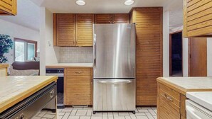 A kitchen with wooden cabinets, a stainless steel refrigerator, and a dishwasher. - Spacious 3-level retreat w/ fireplace, wet bar, deck, tennis, skiing & golf near (Harbor Springs)
