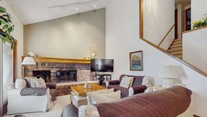 A living room with a fireplace, a sofa set, a coffee table, and a TV. - Spacious 3-level retreat w/ fireplace, wet bar, deck, tennis, skiing & golf near (Harbor Springs)