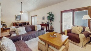 A living room with a sofa set, a dining table, a lamp, and a plant. - Spacious 3-level retreat w/ fireplace, wet bar, deck, tennis, skiing & golf near (Harbor Springs)