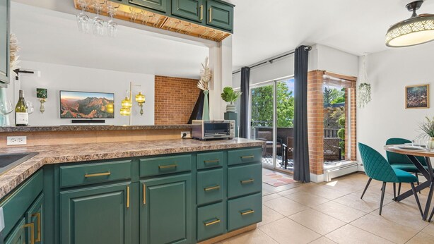 A kitchen with green cabinets, a built-in microwave, and a large island. - The Aviary Near CSU | Pool, Sauna, and Gym (Fort Collins)
