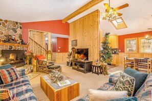 A cozy living room with a fireplace, wooden furniture, and a staircase leading to another level. - Family-friendly rustic cabin next to the slopes of Crystal Mountain (Thompsonville)