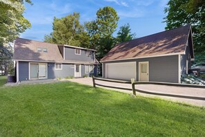 A residential property with two attached garages, a covered patio, and a fenced yard.
